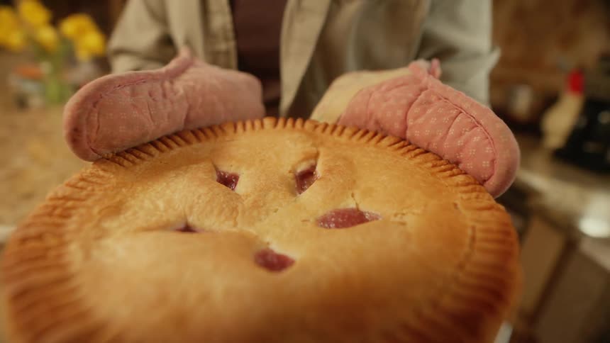 A woman carries a pie over to the counter