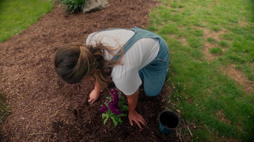 Woman on her knees in a garden digging a hole