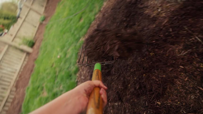 A gardener moves dirt from the wheelbarrow to the ground