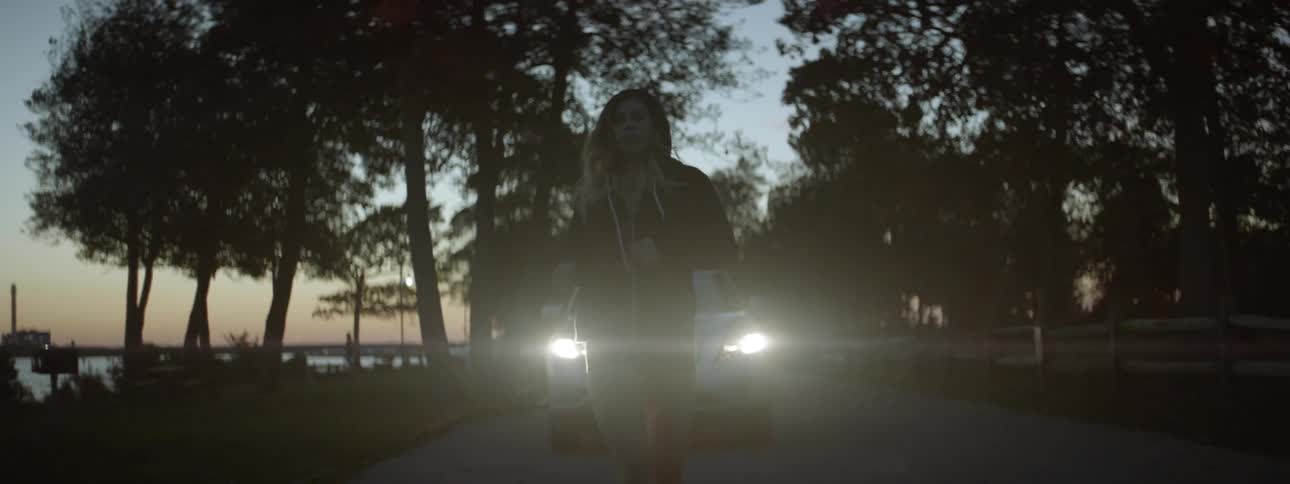 Woman jogging at night with a car following