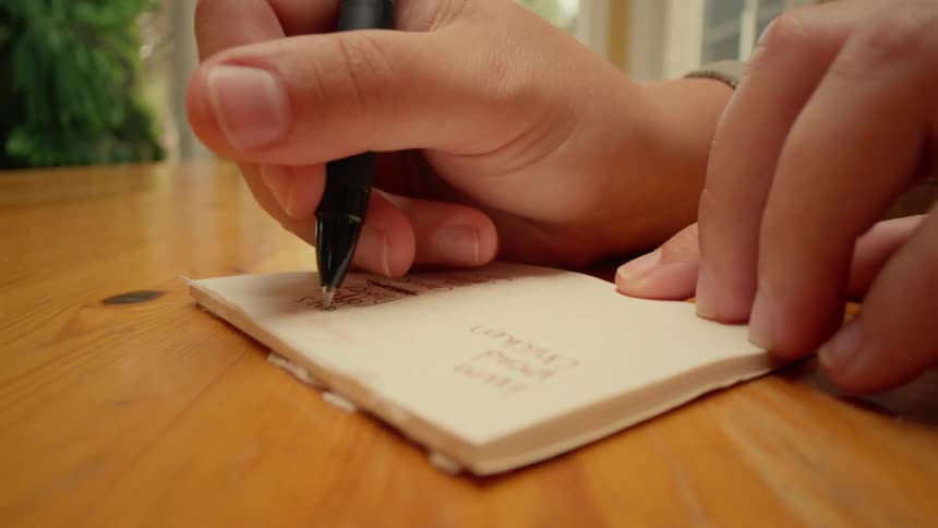 A person scratches things off his list with a pen