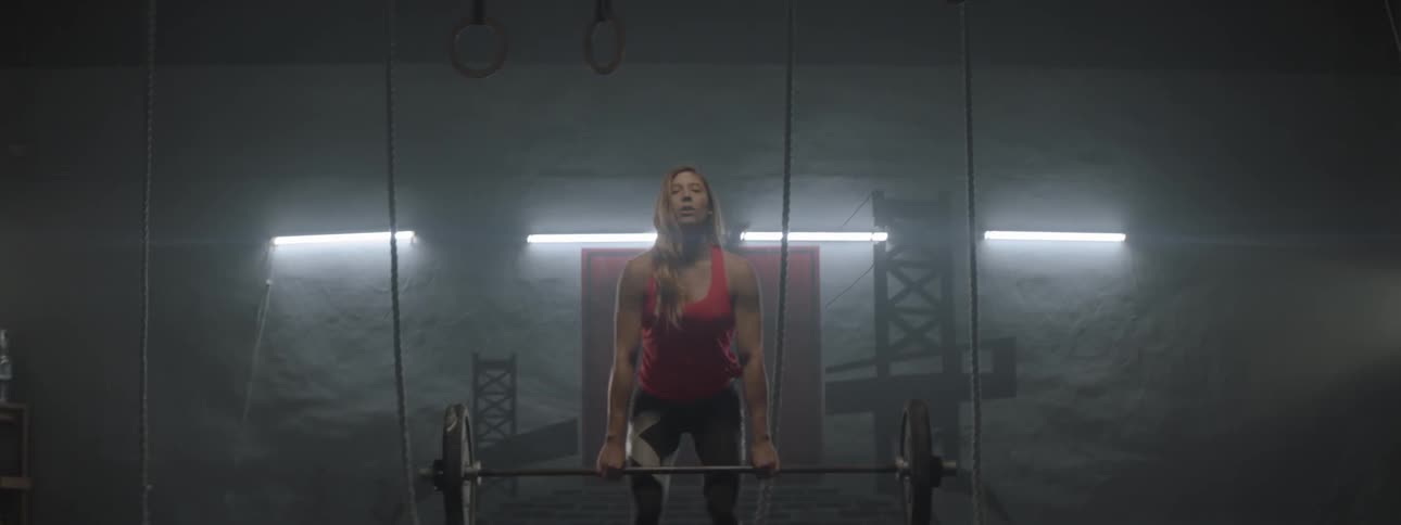 A woman lifts a barbell weight above her head