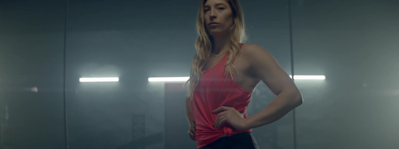 A woman standing in a room in exercise clothes and staring at the camera