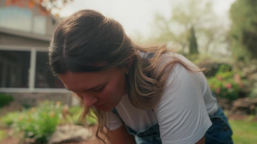 Woman crouched down working in the backyard of a house