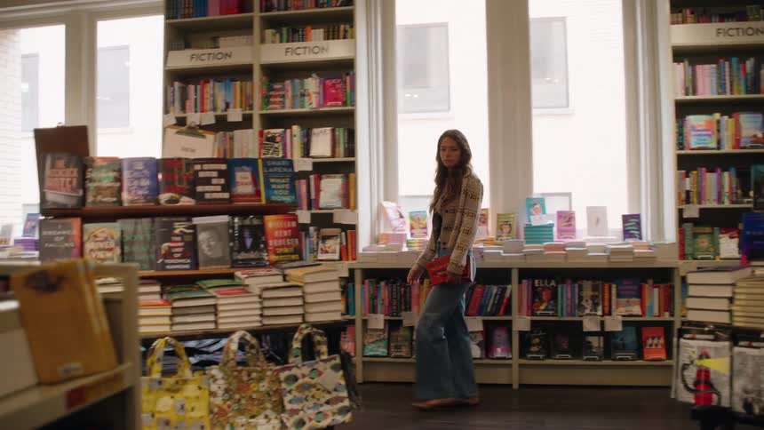 Woman carrying a book looks through a bookstore during the daytime