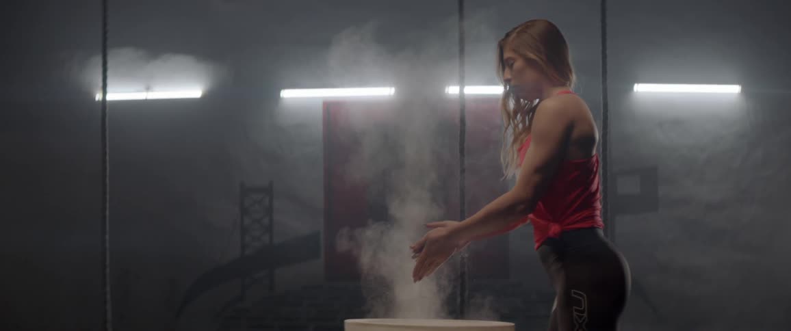 An athlete rubs chalk on her hands