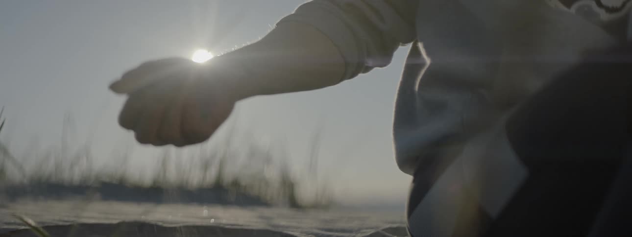A person holding sand in her hands and dropping it out slowly