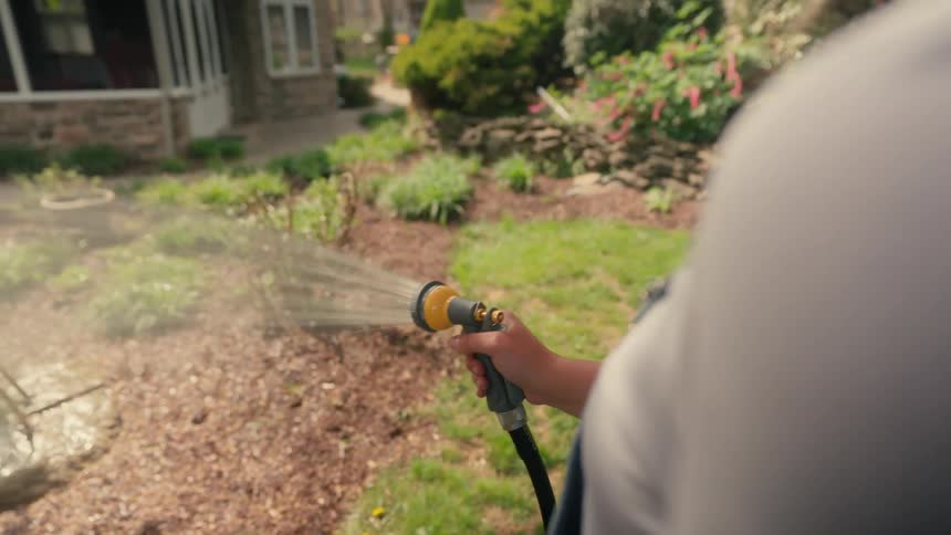 Closeup of woman watering plants in a garden during the day