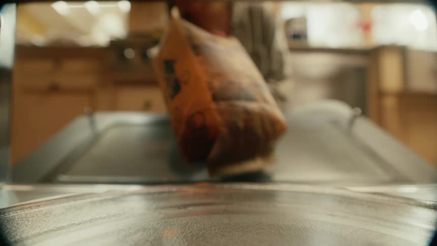 Closeup of woman picking packaged food from a microwave