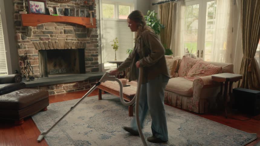 Woman vacuuming large area rug and hardwood flooring in living room