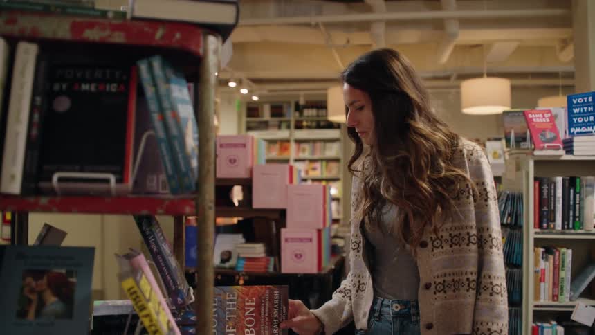 A young woman walks around and looks at books in a book store