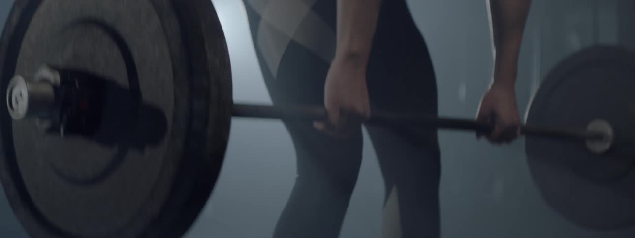 A person lifts weights behind a spotlight
