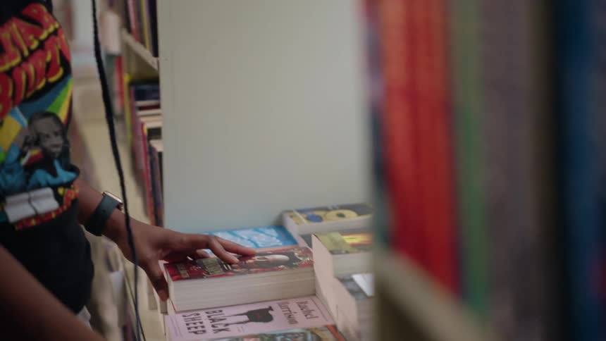 A black lady arranges books in a bookstore at daytime
