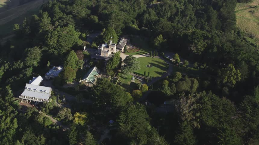 A large mansion sits on the hill surrounded by trees