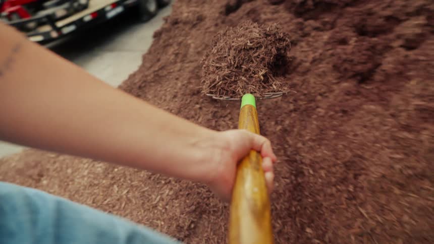 A person is shoveling soil into the wheelbarrow