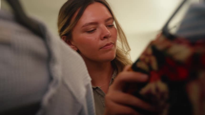 Woman opening closet looking around then pulling out a blue dress