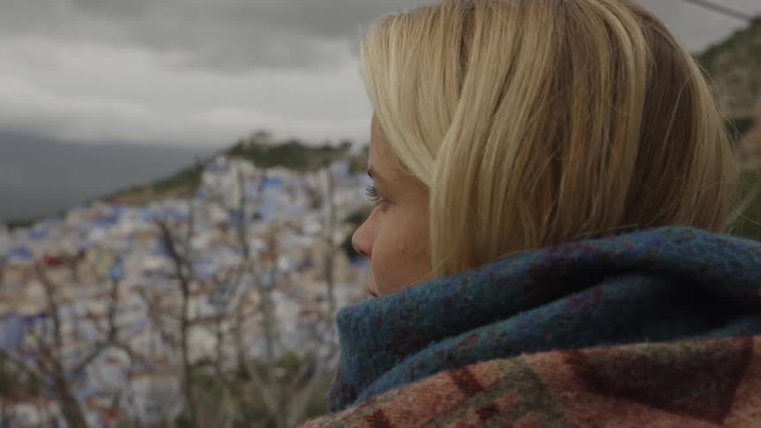 Blonde woman contemplates a city in the distance on a cloudy day