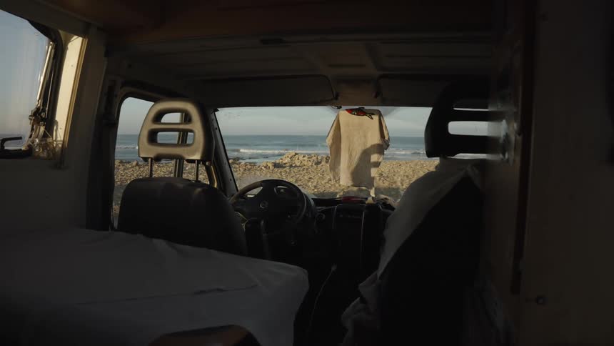 View of the interior of a van parked near a rocky ocean beach