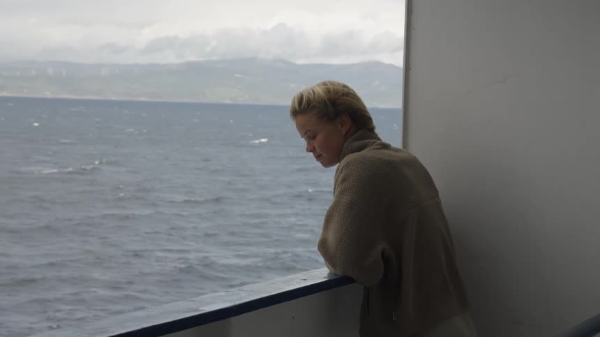 Woman in coat catching the breeze from a moving boat
