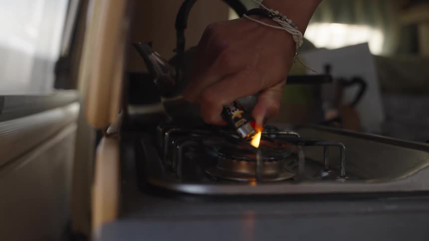 A person lights a gas cooker with a lighter