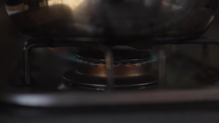 A stove burner with flames of fire cooking a pan that is on top