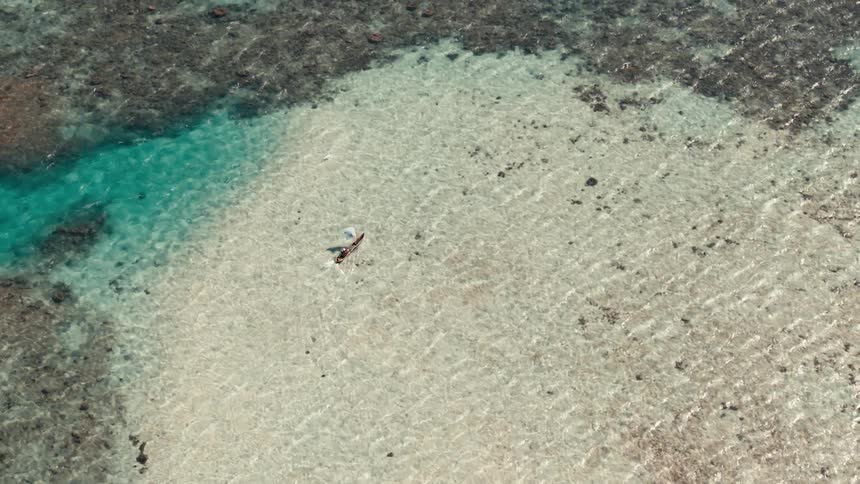 Kayaking in crystal clear water over white sand ocean surface near coral reefs
