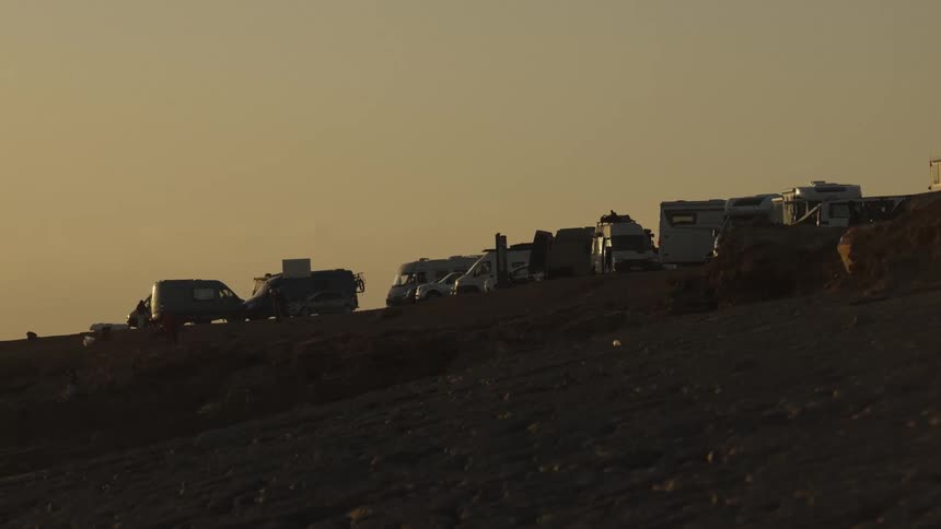 Vehicles parked on top of a hill under the golden light of dusk
