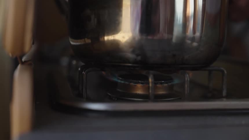 A person puts a pot on the stove top