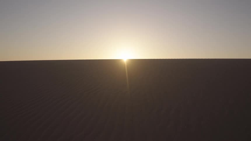 The sun is rising on the desert