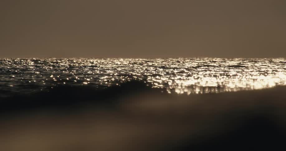 Sunlight shines upon the water as it ripples and moves under a dark cloudy sky
