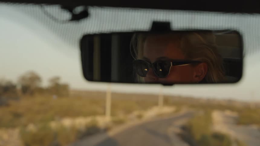 Woman in the reflection of the cars rearview mirror