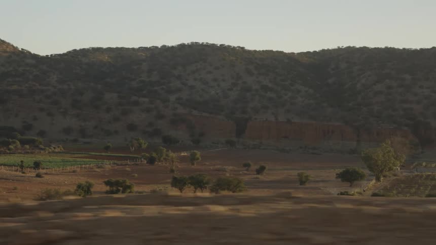 Moving view of agricultural fields with mountains in the background