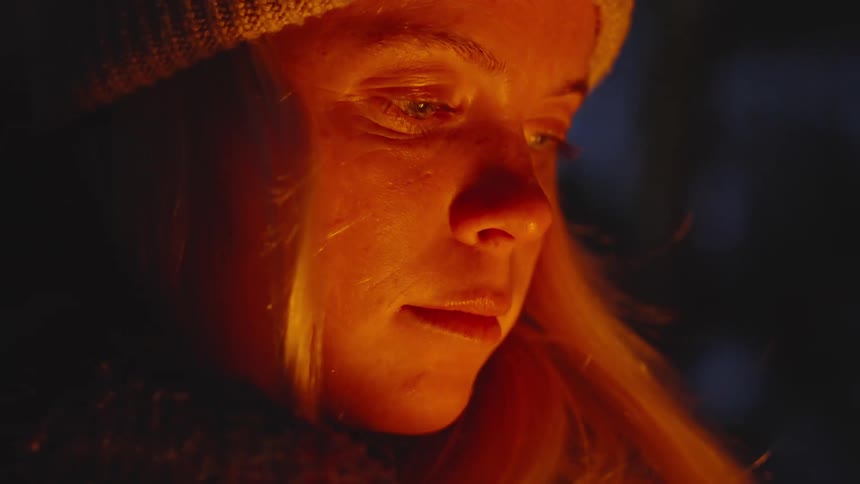 A woman is warming up at a campfire