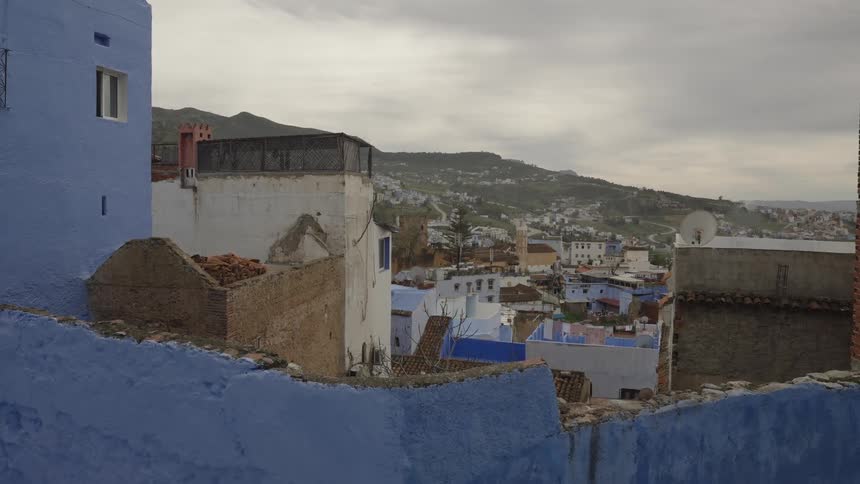 Overlooking a hillside moroccan town with blue painted buildings under overcast skies