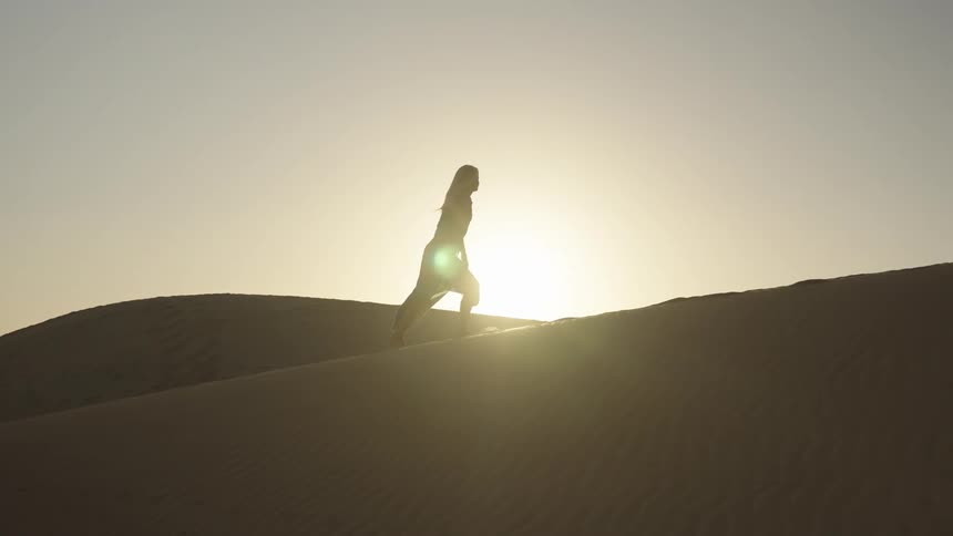 A woman walking in a desert under the sunlight