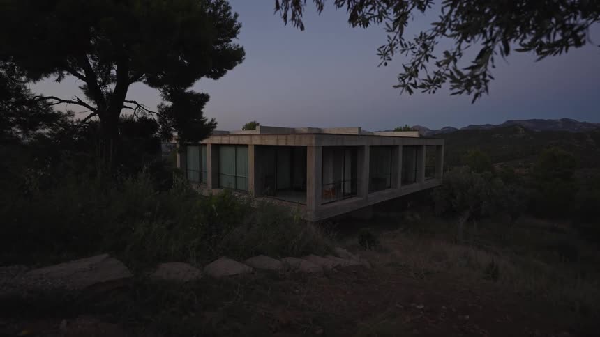 The exterior of a quadrangular house with glass walls in a green environment all around