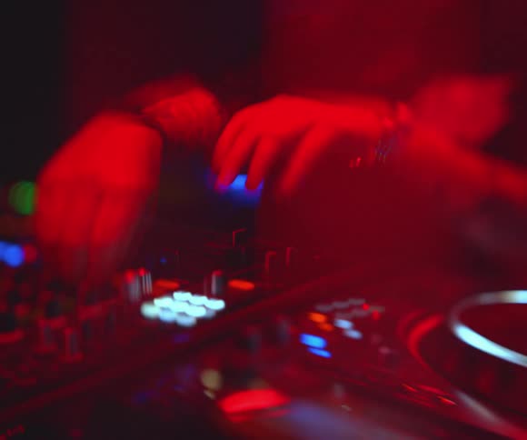 The dj is playing music on the soundboard