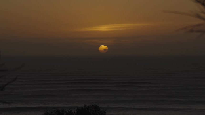 Ridge patterned sand stretches into the distance beneath a setting sun
