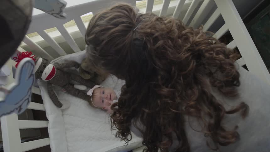 A woman lays a baby in a crib
