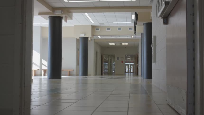 Large columns line a spacious area in a large building while a person walks by in the distance