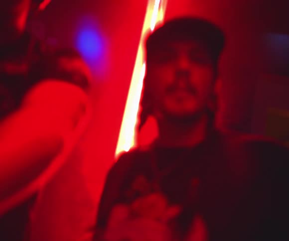 Man dances in a crowd in a club lit by colored lights