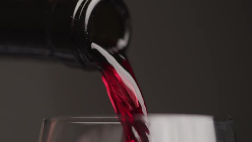Closeup of a person pouring red wine into a wine cup