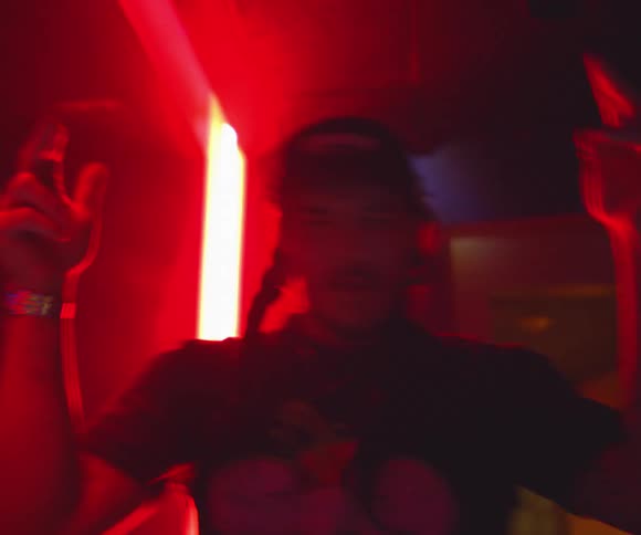 Man dancing with his arms raised under red lights