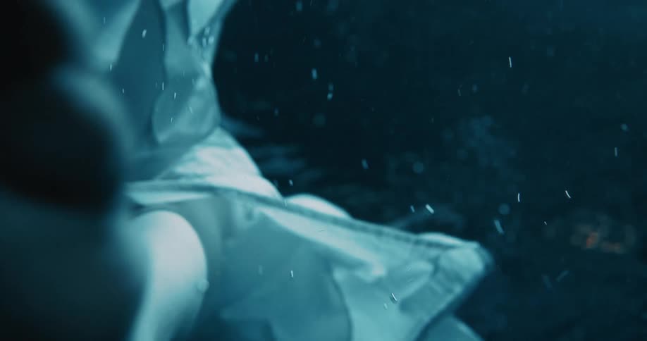 Person in a white dress stands in the depths of the ocean