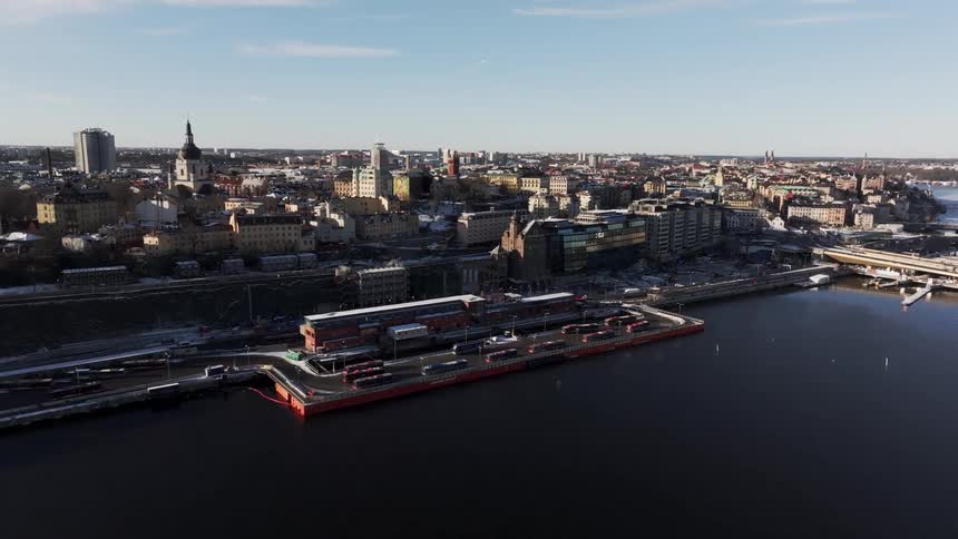 Aerial view of a european waterfront city with historic buildings modern structures and trains along the docks on a clear day