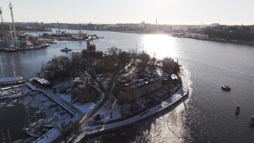 Boats pass by the small island with buildings on it