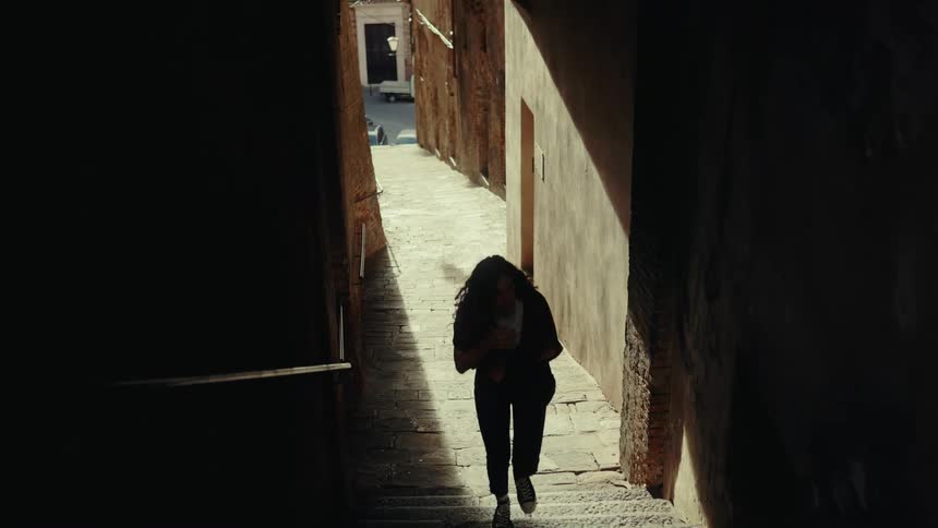 A woman walks up the stone steps in the alley