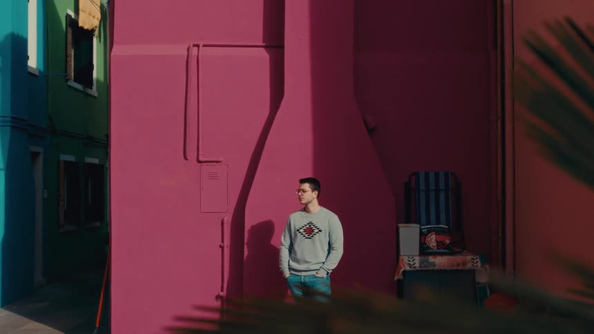 A man standing on the street with his hands in his pockets looking thoughtful
