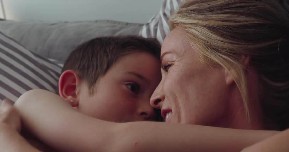 A mother and son lay in bed hugging