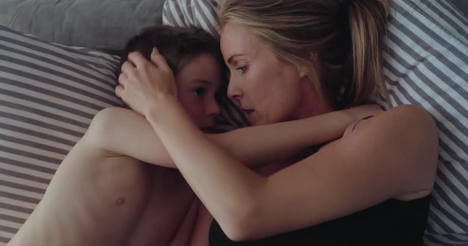 A mother and son are hugging in bed